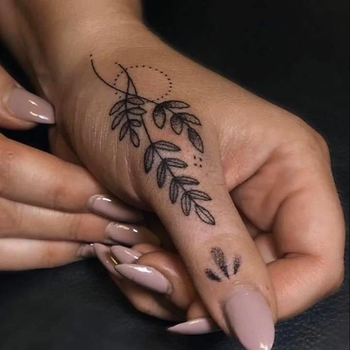 Hình xăm cành lá mảnh kéo dài trên mu bàn tay
