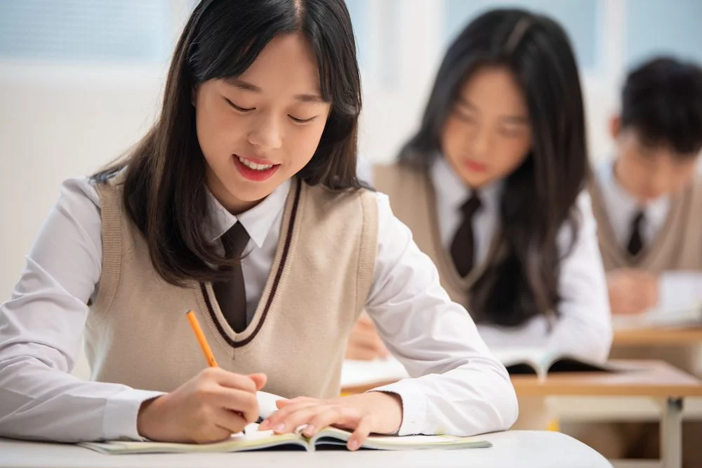 Nữ sinh cấp 2 chăm chú ghi chép bài trong lớp học