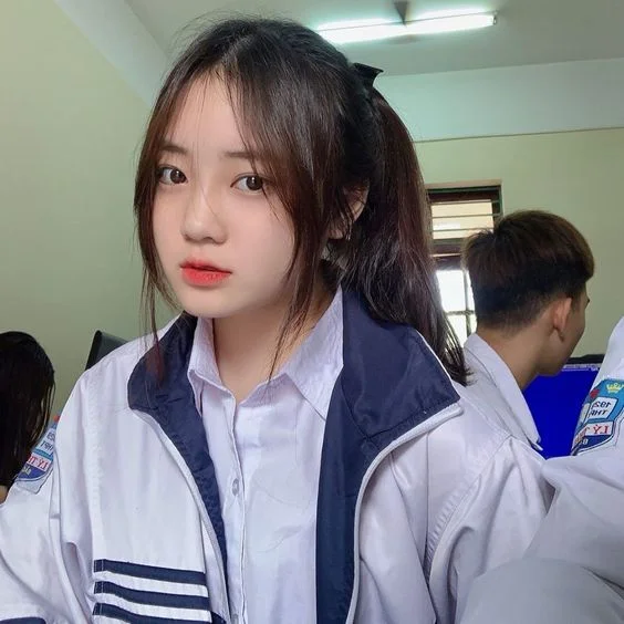 Nữ sinh cấp 2 mặc áo khoác đồng phục chụp ảnh trong lớp học